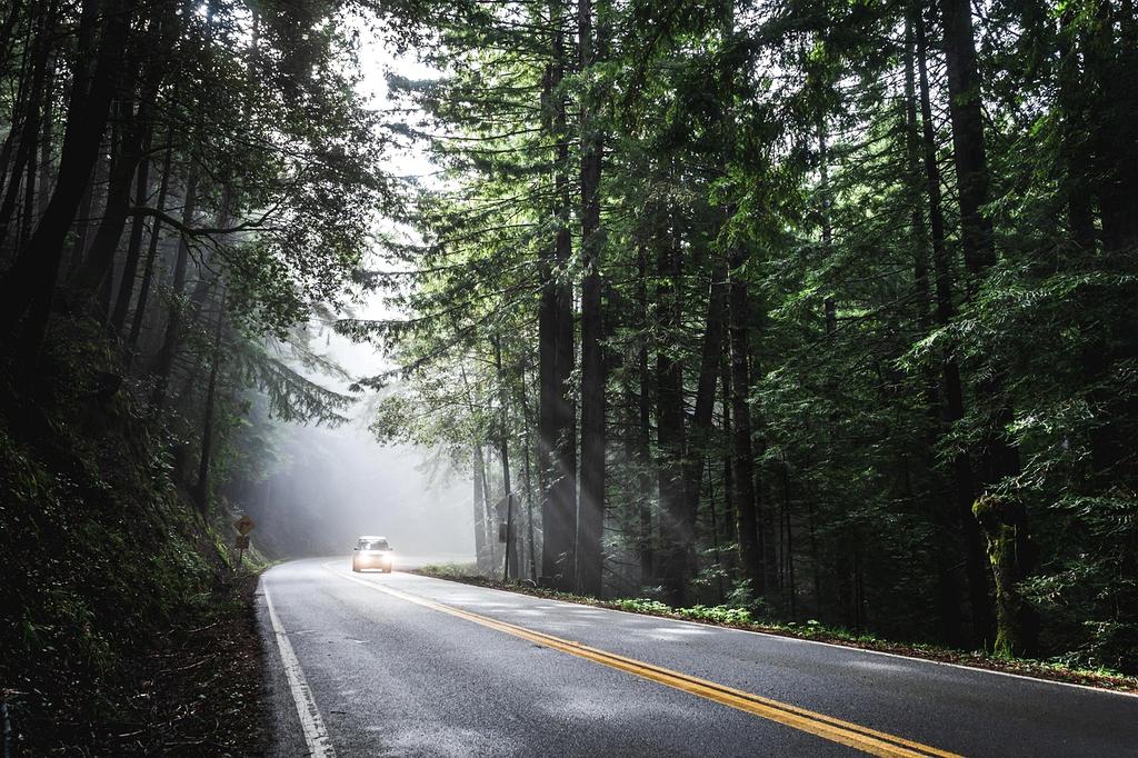 Traveler using a reusable water bottle at a mountain stream